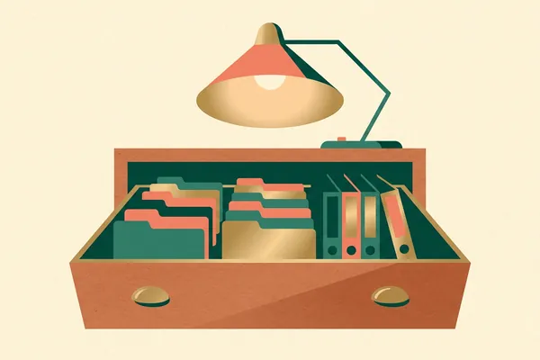 An open card-file drawer full of labelled folders, under a desk lamp.
